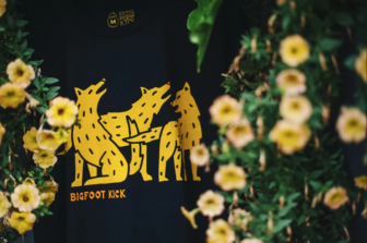 Bigfoot Kick wolf tshitrt with green and floral surroundings