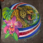 Detailed chalk drawing of a roaring jaguar surrounded by tropical leaves, a pink orchid, and a red, white, and blue ribbon reading “Pura Vida.”