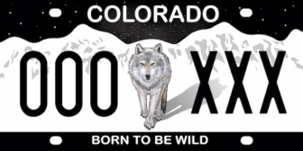 Illustrated Colorado specialty license plate featuring a gray wolf walking in front of snow-covered mountains, with the slogan “Born to Be Wild.”